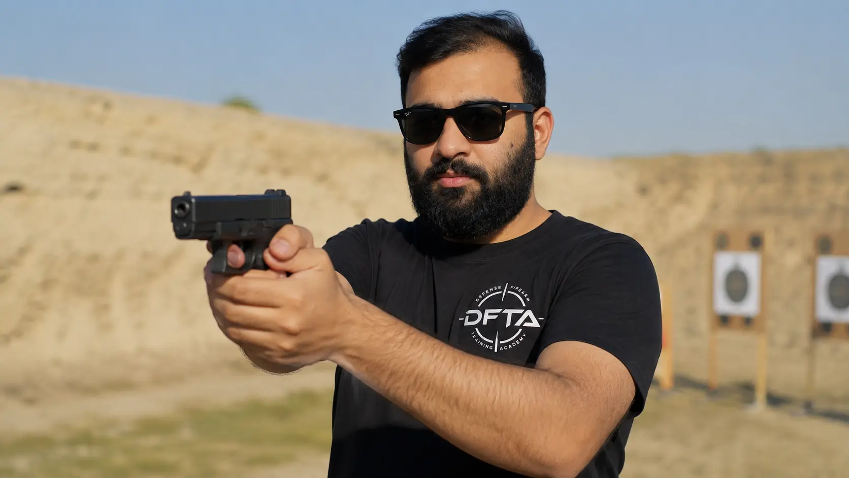 Instructor demonstrating a two-handed pistol grip on the outdoor range